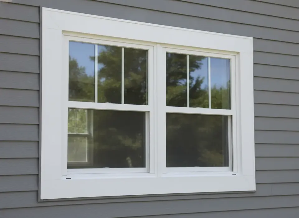 New white vinyl replacement window in gray siding